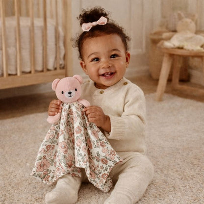 bebe-fille-souriante-avec-doudou-ourson-rose-dans-ses-mains