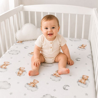 bebe souriant assis sur matlats avec la drap housse lit bebe ourson nuage