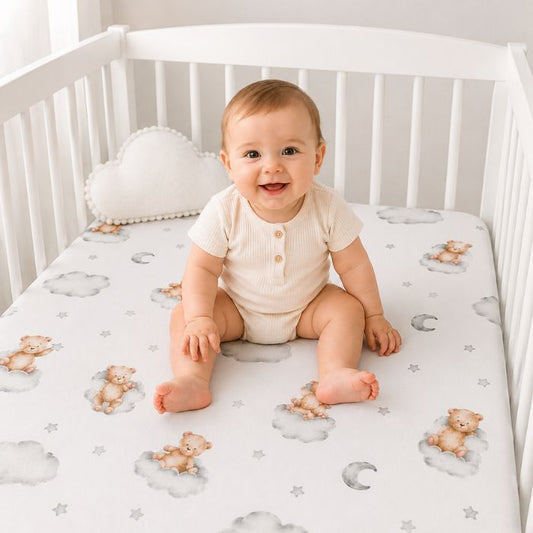 bebe souriant assis sur matlats avec la drap housse lit bebe ourson nuage