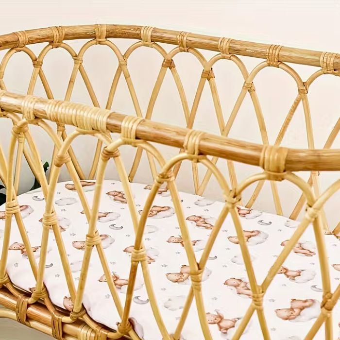 Drap housse lit bébé ourson nuage installé dans un berceau vintage en rotin tressé