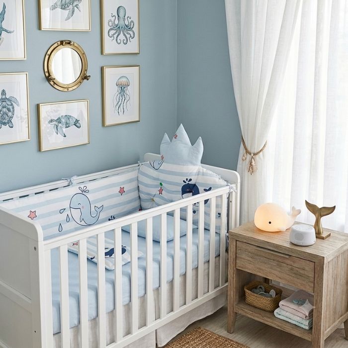 tour de lit bébé 5 pièces baleine dans lit blanc à barreaux dans la chambre de bébé