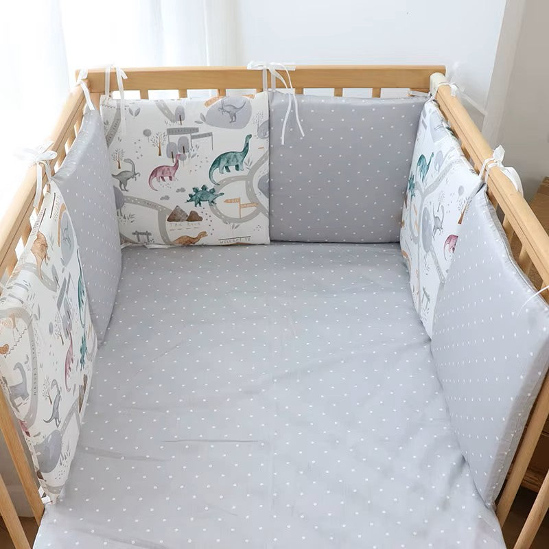 tour de lit bébé complet dino installé dans un lit en bois à barreaux 